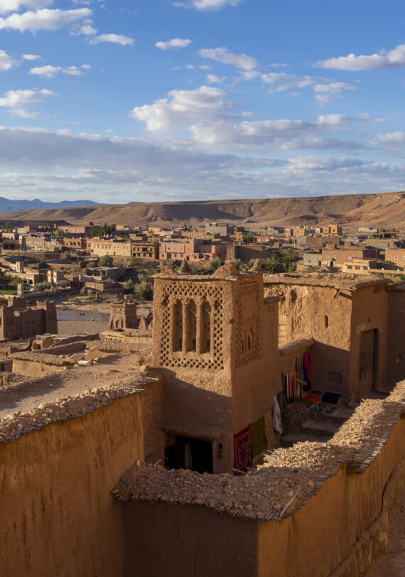 Village rural du Haut Atlas au coucher du soleil avec sentier de randonnée et sommets enneigés, découvert lors de nos voyages organisés en Afrique