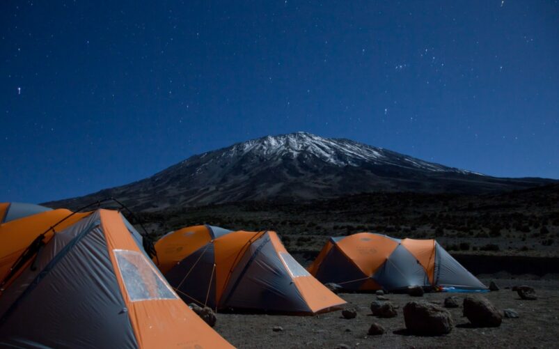 Tentes orange sous le ciel étoilé au pied du Kilimandjaro lors d'une randonnée Tanzanie.